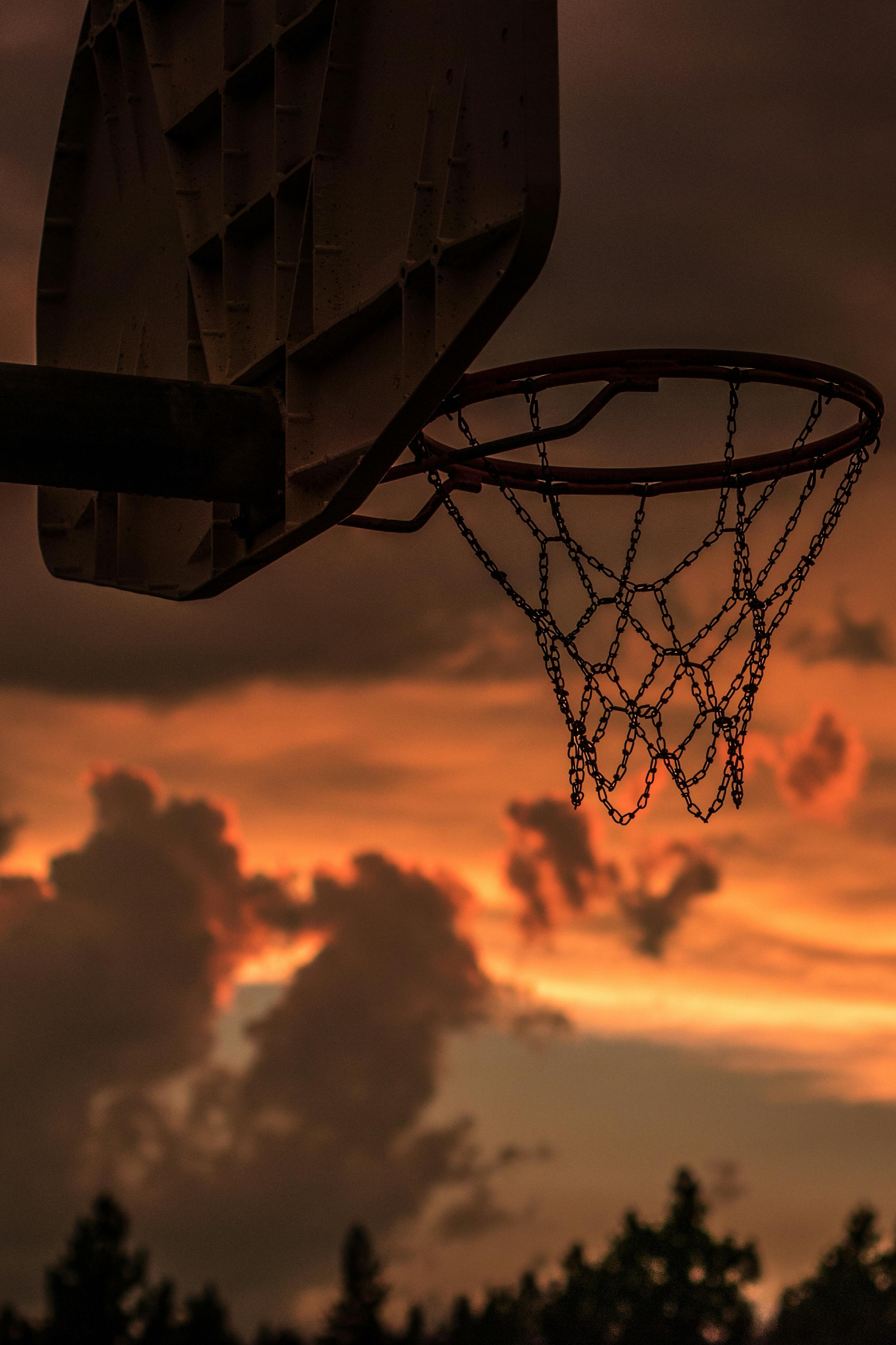 Fillet de basketball avec un coucher de soleil derrière.