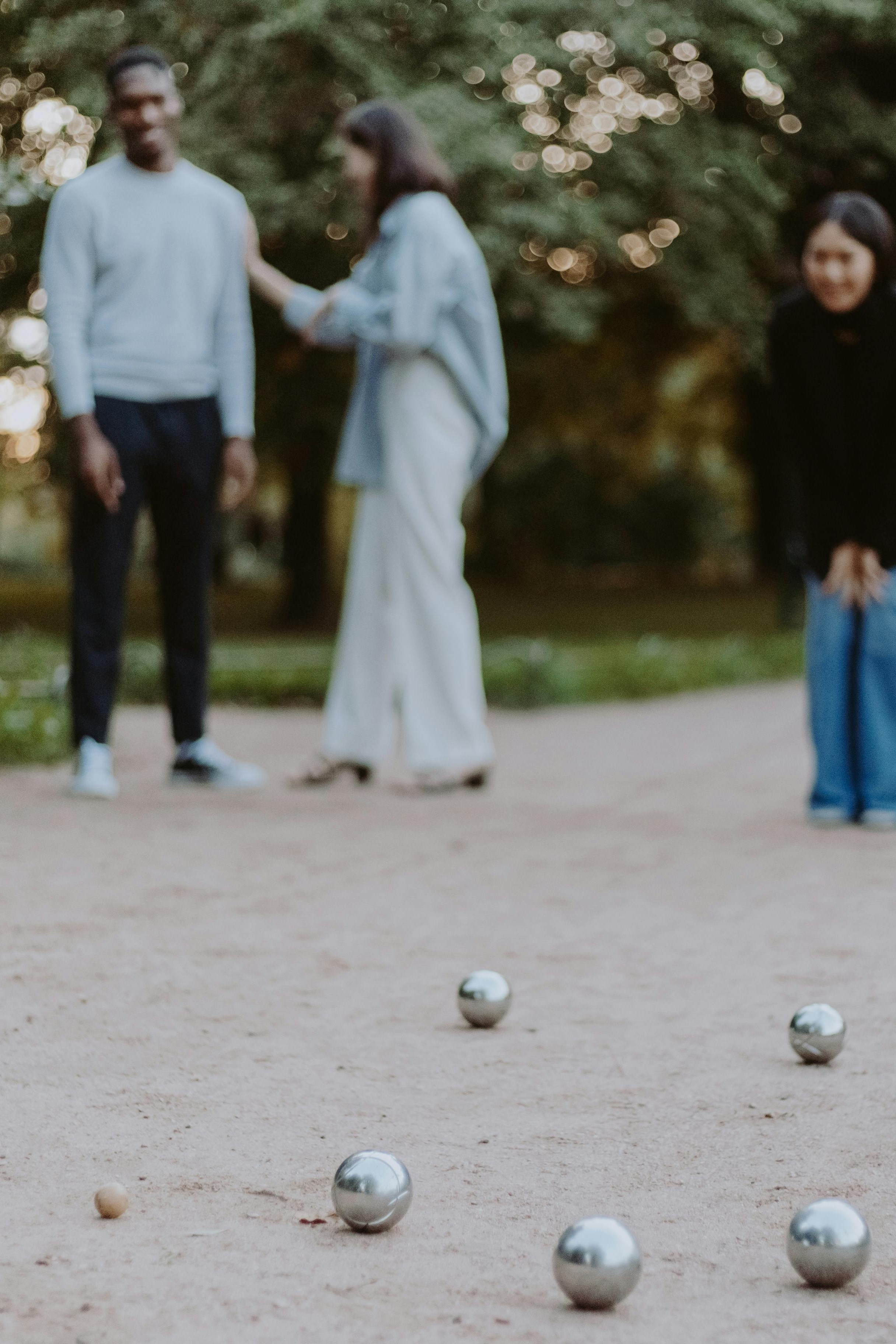 Petanque balls on a field with people blurry in the back.