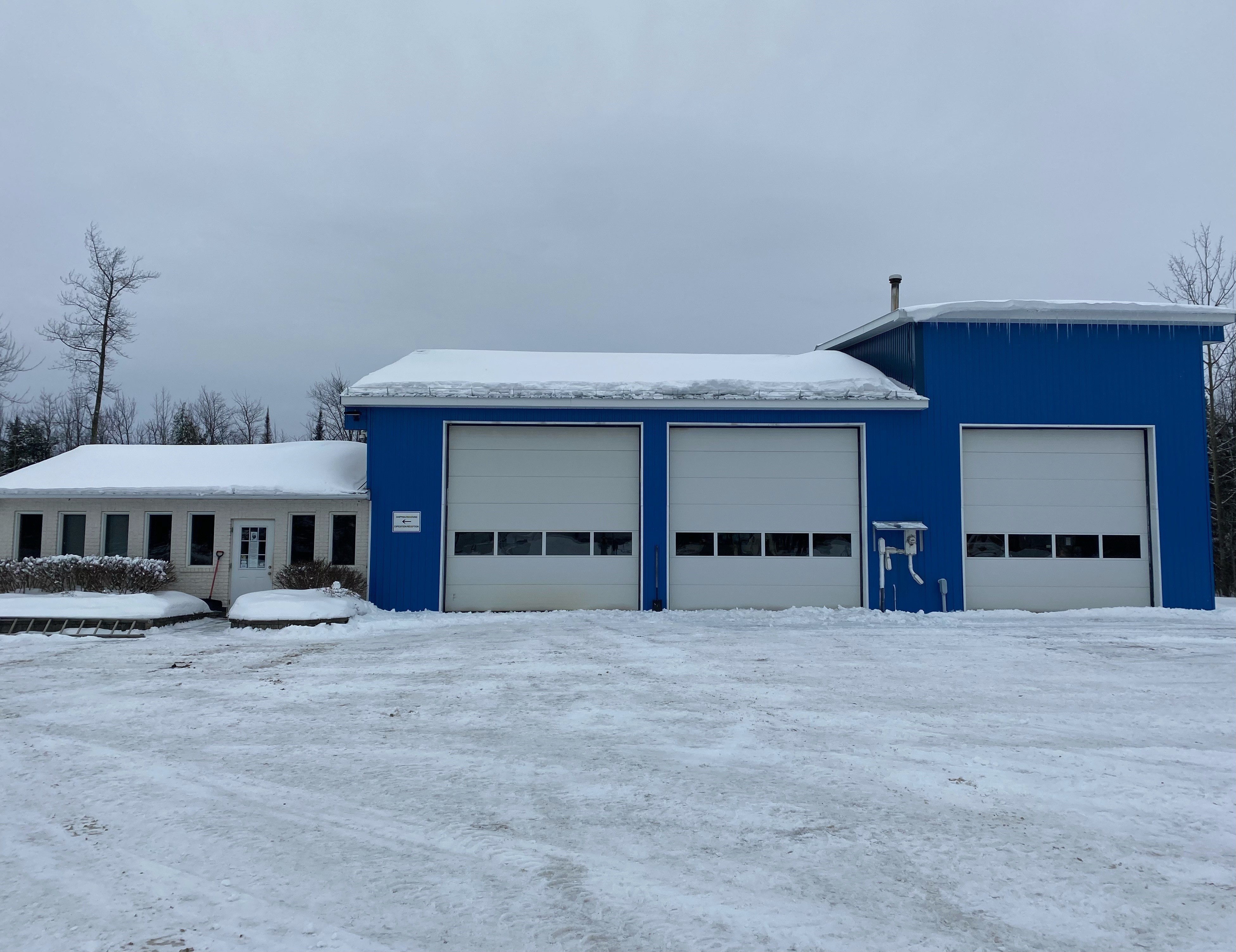 Rectangular blue building with three garage doors