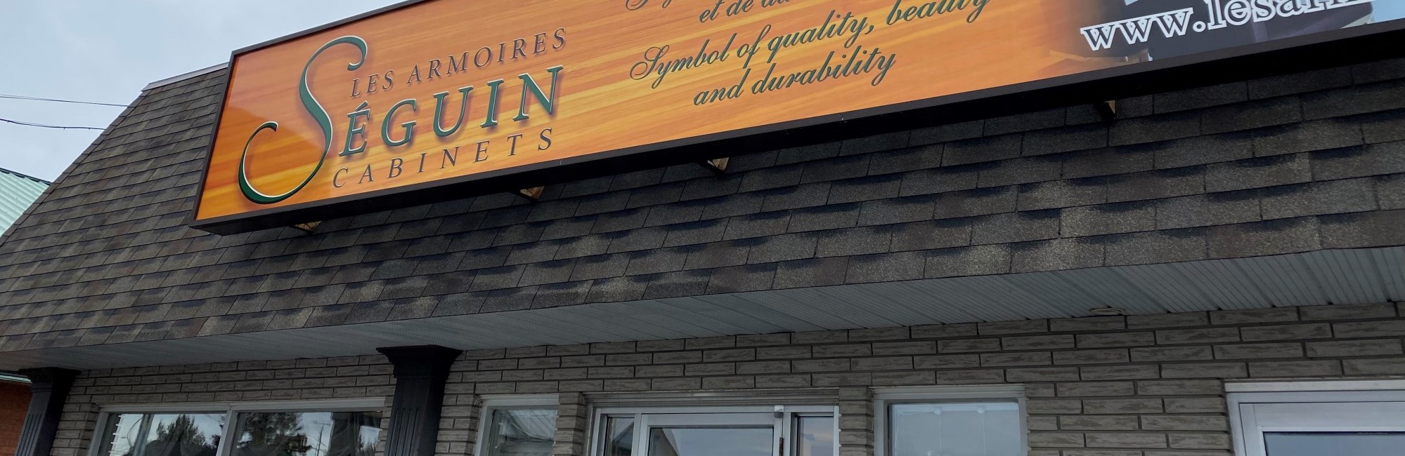 rectangular building with large windows and brown roof, orange sign that reads the company name