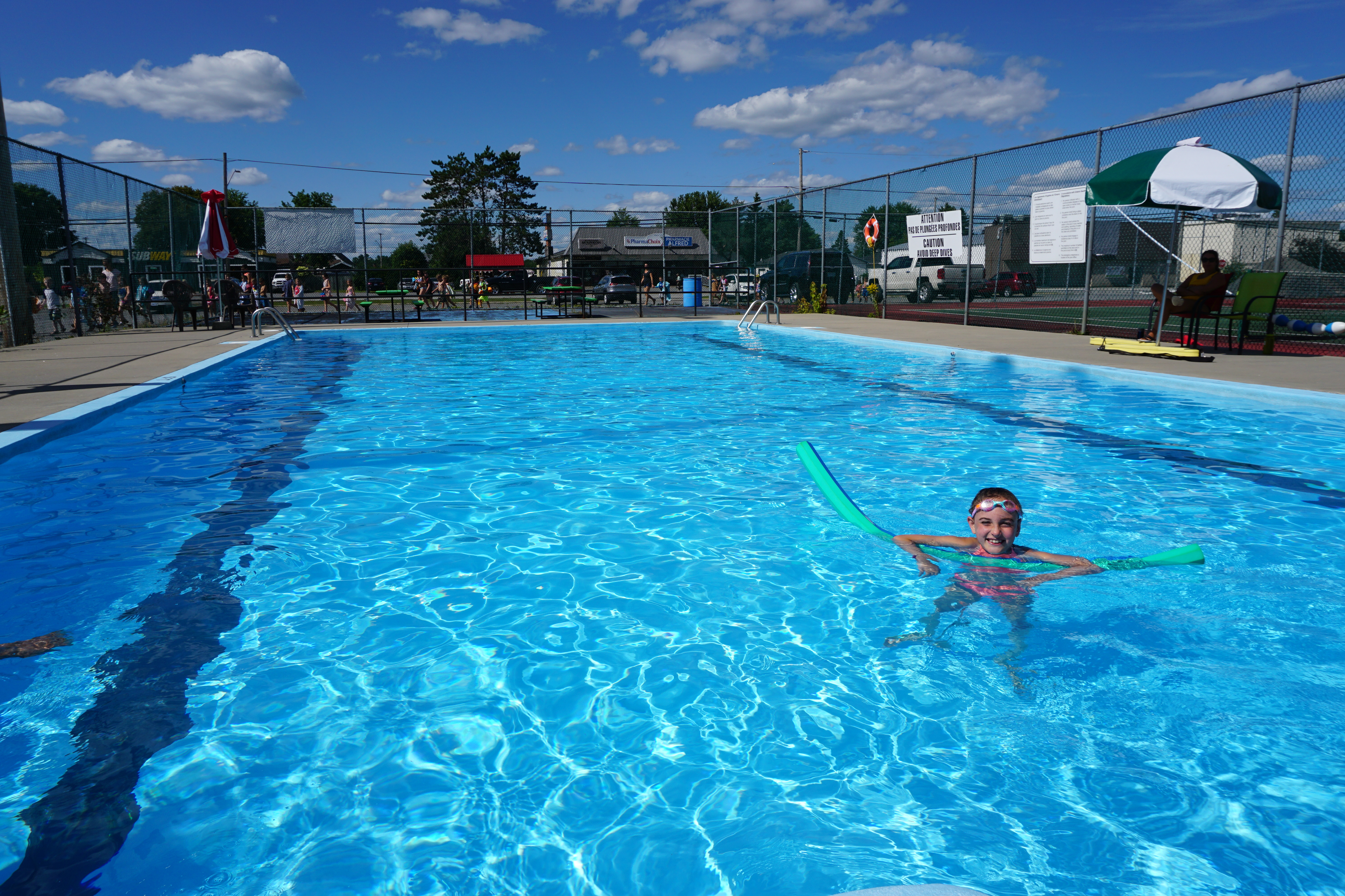 Outdoor rectangular pool with kids playing in it.