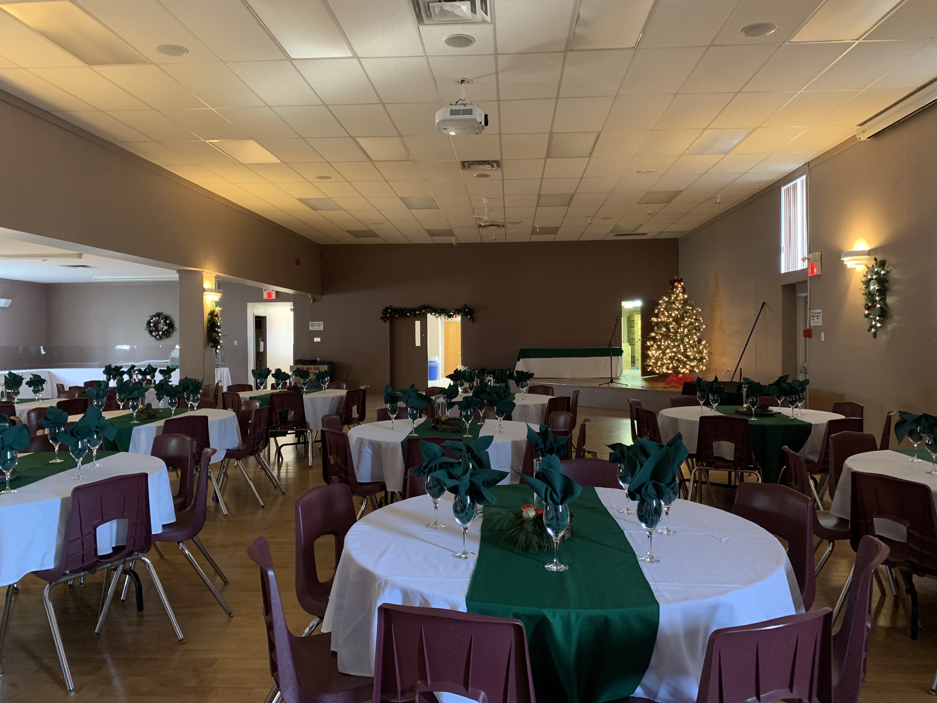 Multiple round tables decorated for Christmas and a Christmas tree in the back