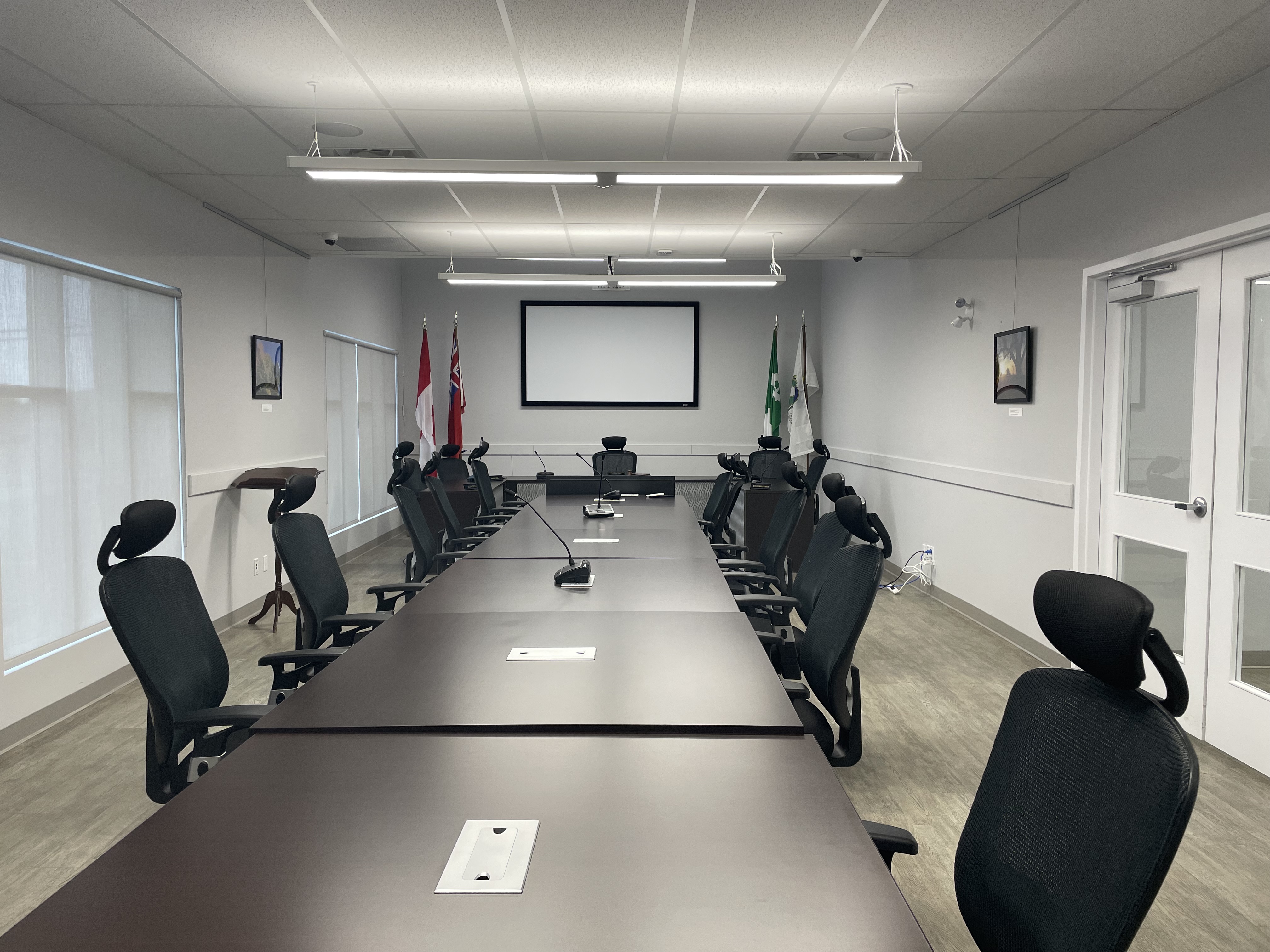 A long table with chair on each side and a projector screen at the back