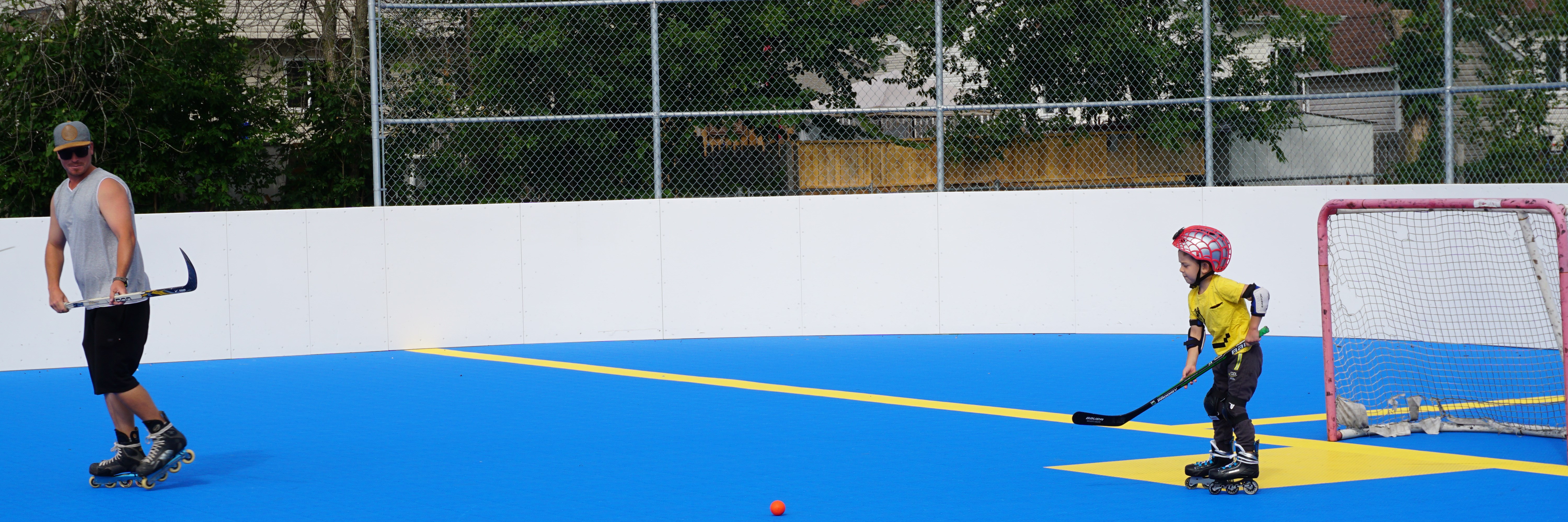 a man and a kid playing hockey on the dekhockey surface