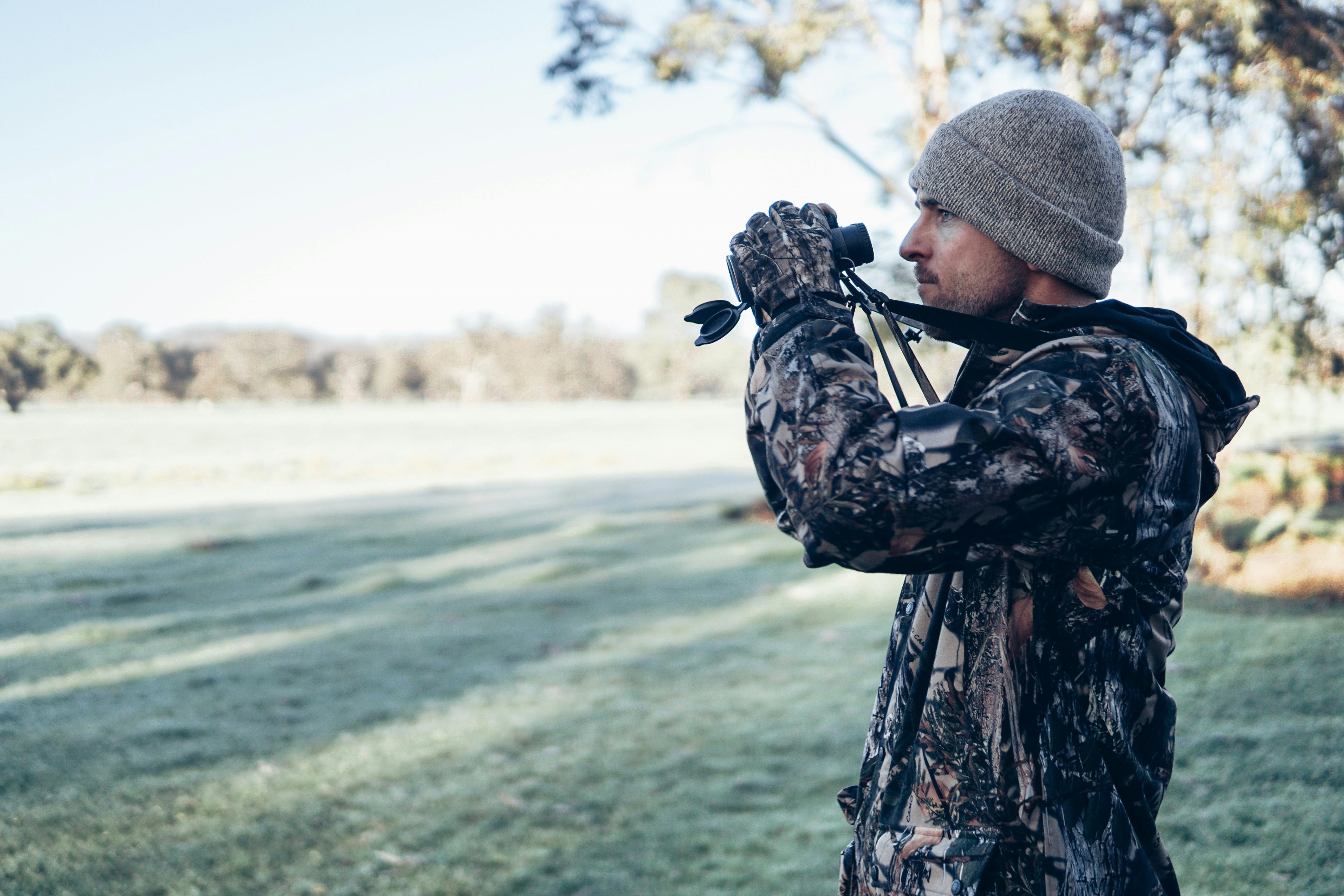 Hunter looking at a field with binoculars