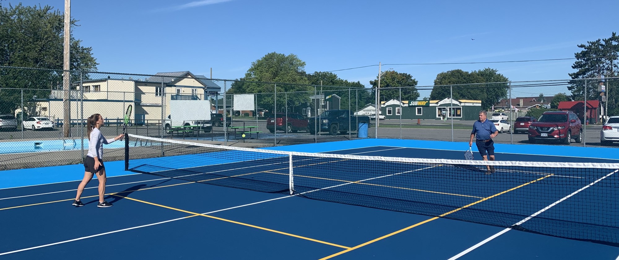 Jeune femme et homme plus agé qui jouent au tennis