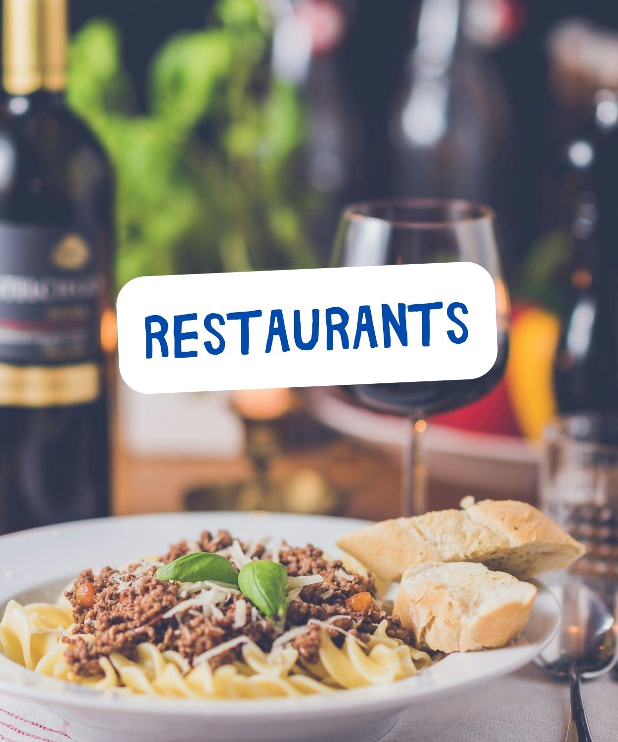 View of a plate full of pasta, and a wine glass at a restaurant table