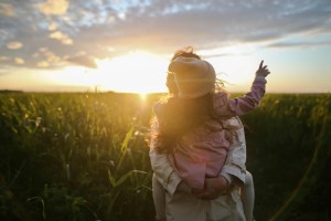 Une dame avec un enfant dans les bras et un coucher de soleil