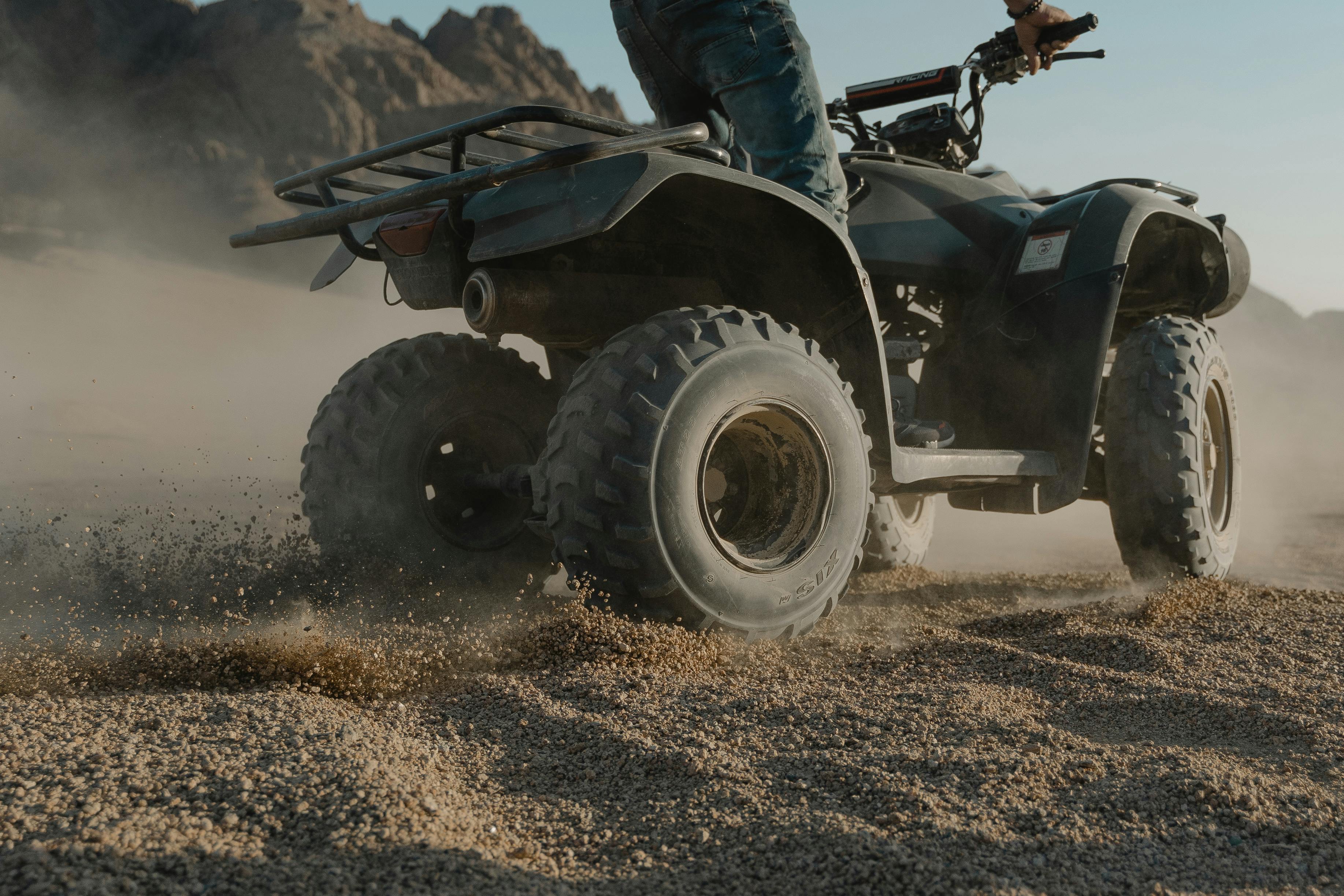 A person driving a four wheeler in the sand. 