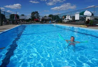 Child floating in an outdoor pool in summer
