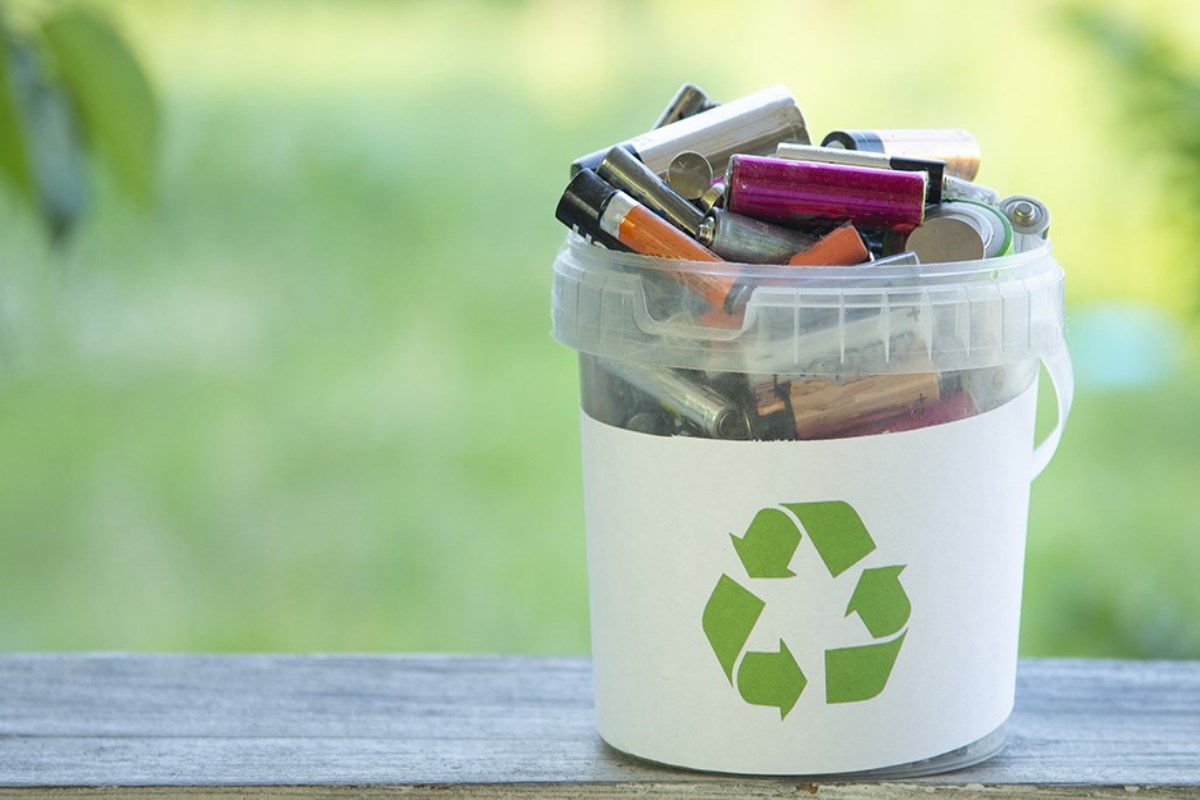Pot avec le logo de recyclage rempli de batteries