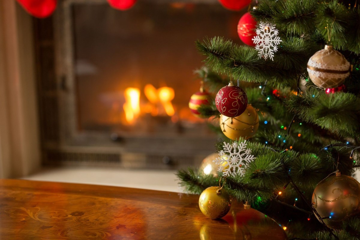 Christmas tree with red and gold baubles in front of a fireplace