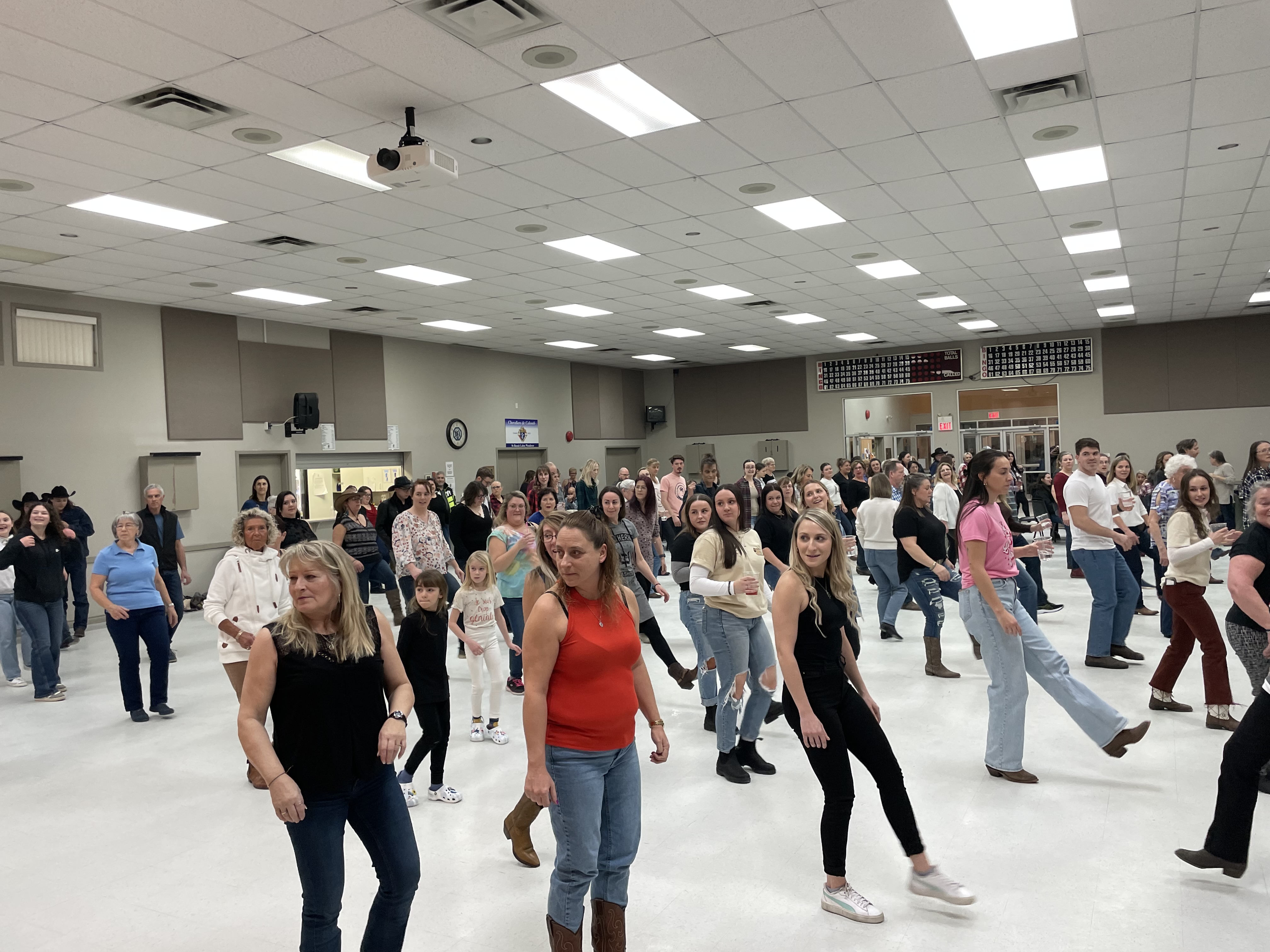Un groupe de personnes fait de la danse en ligne dans un salle communautaire
