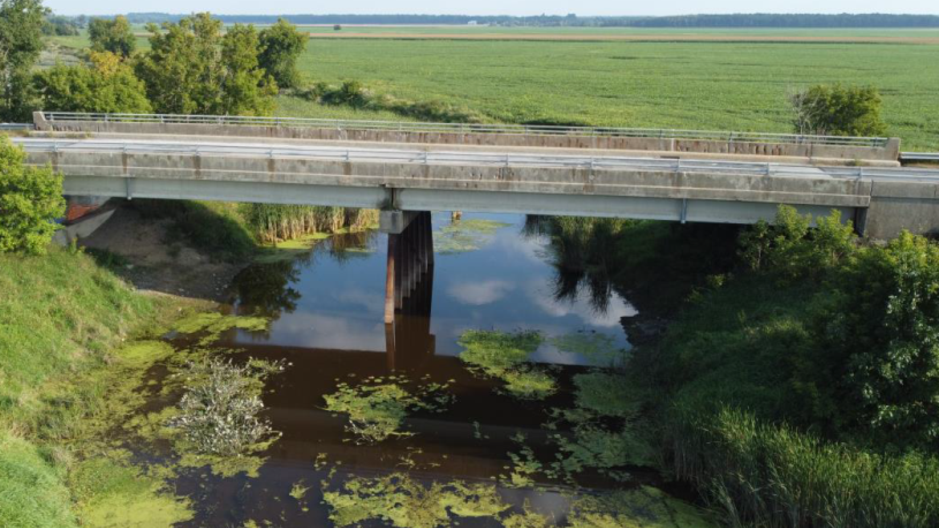 Bridge over a river with green fields in the background.
