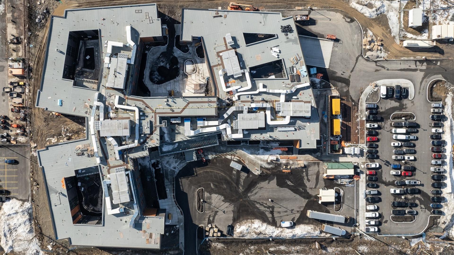 Aerial view of a large building complex with surrounding snowy landscape.