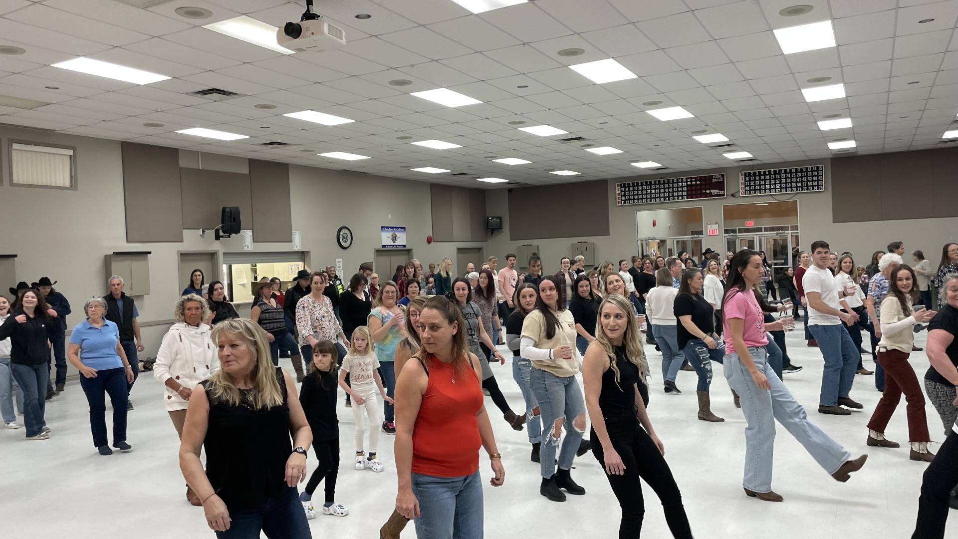 Group of people line dancing in a public hall