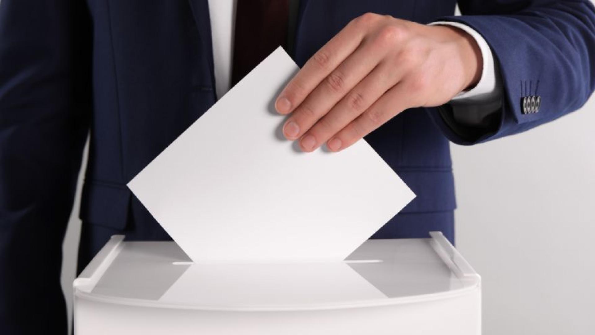 Person putting voting ballot in a sealed box.