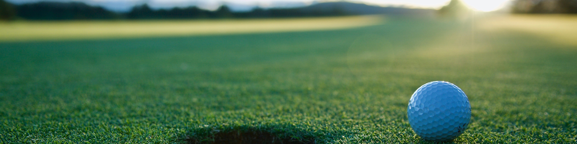 A golf ball close to the hole with empty golf course behind