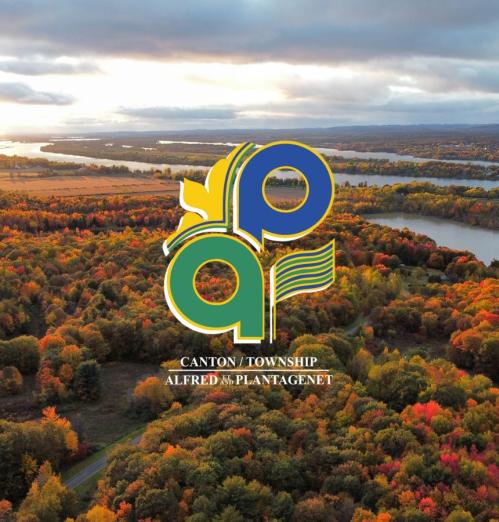 Aerial view of trees in the fall next to a river with the Township logo