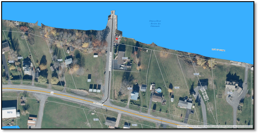 Vue aérienne d'un paysage côtier avec route et maisons près de l'eau bleue.